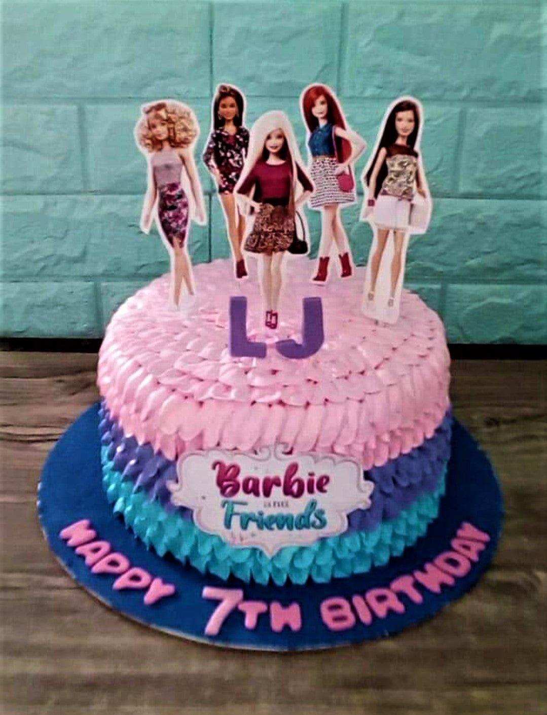 Barbie and Friends themed pink cake with ruffled icing, character printouts, and a blue base board with a birthday message.