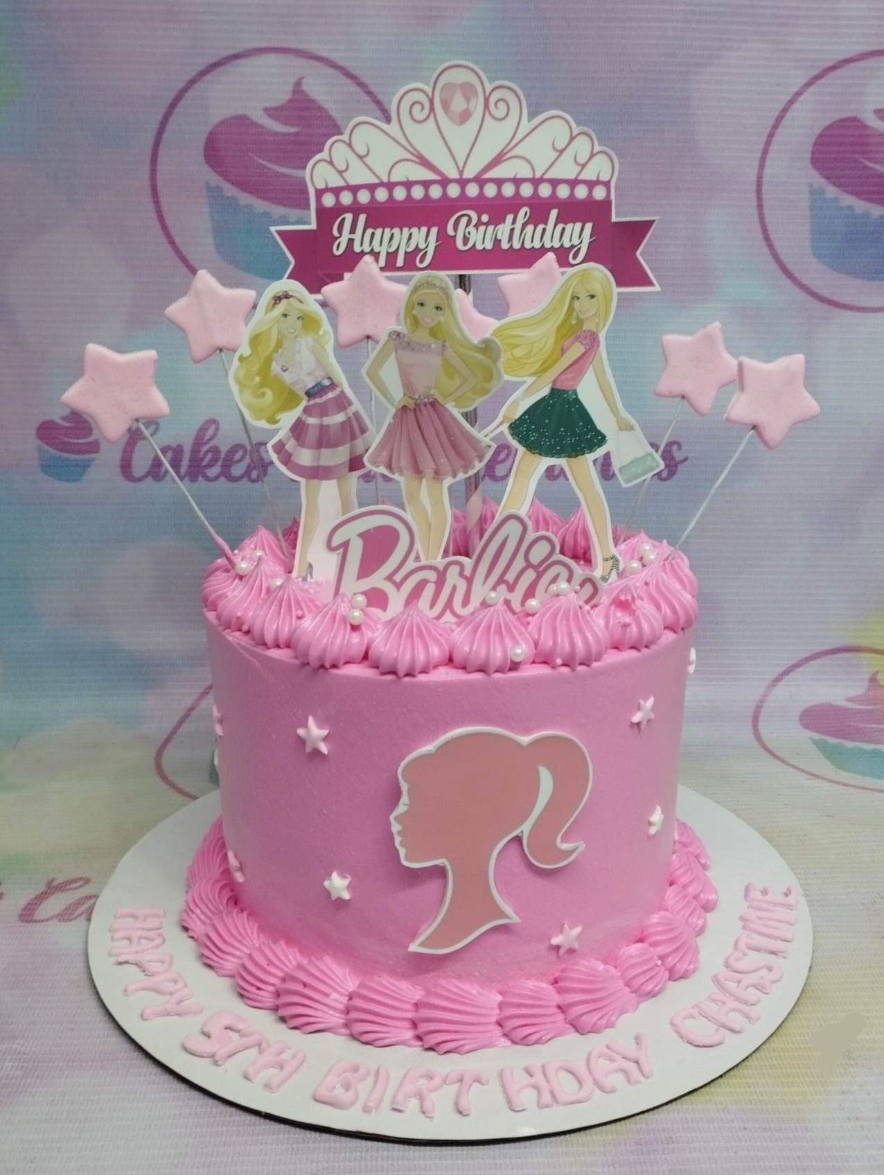 Pink Barbie themed birthday cake with character printouts, a crown topper, and pink icing swirls.
