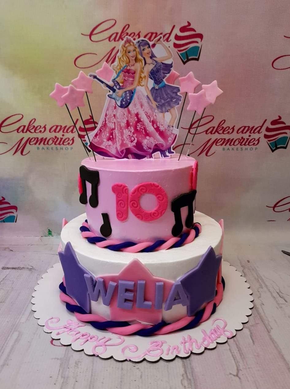 Pink and white 2-tier Barbie Rock 'N Royals themed birthday cake with music notes, stars, and character toppers.