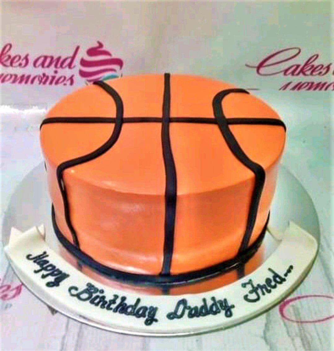 Orange basketball-themed birthday cake with black icing lines and a white banner message for Daddy Fred.