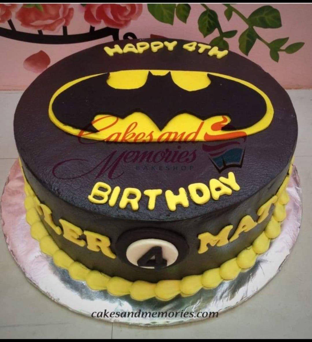 Batman themed birthday cake with black icing, yellow Batman logo, and yellow gumpaste letters for a 4th birthday celebration.