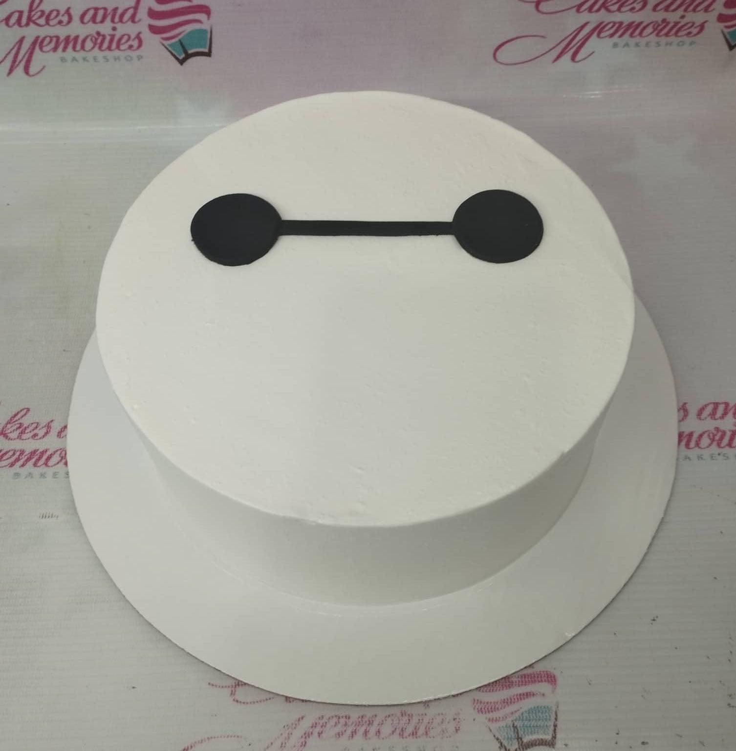 Minimalist white round cake featuring the black Baymax face design on top.