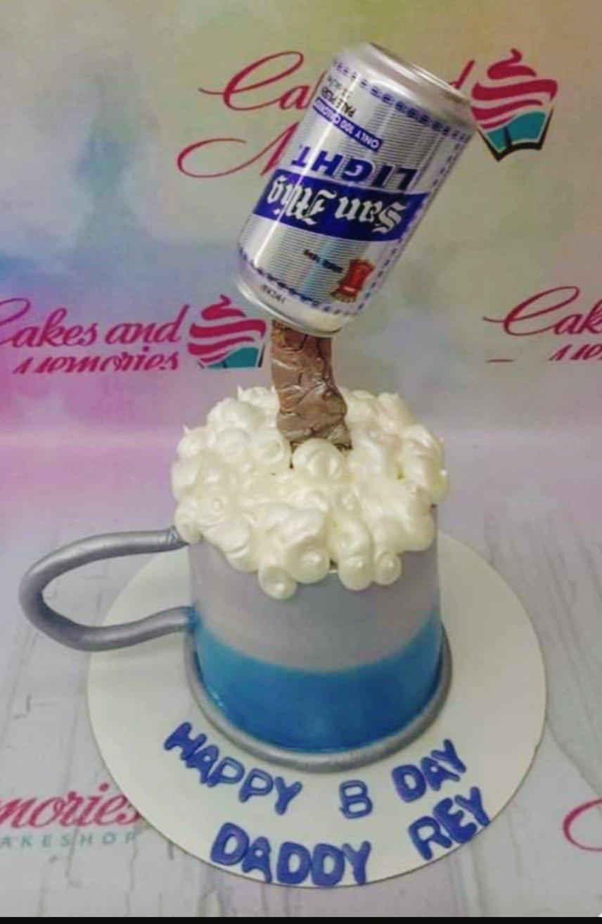 San Miguel Light beer mug cake with a gravity-defying beer can topper and white icing foam on a blue and gray base.