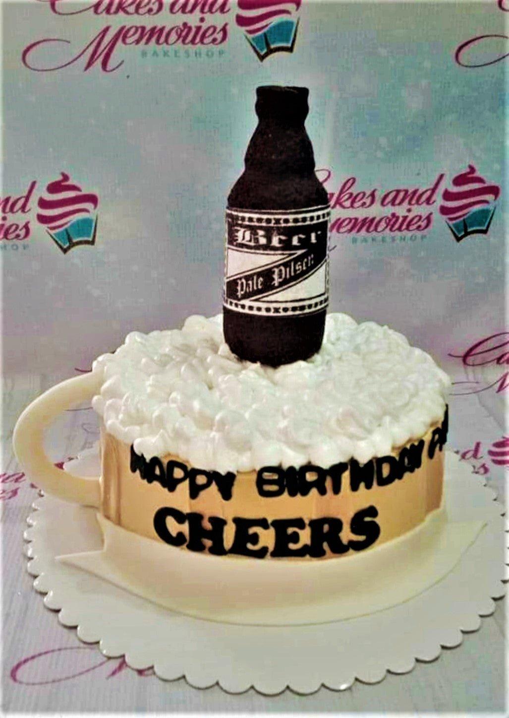 Beer mug cake with white icing foam and a black beer bottle topper on a gold base.