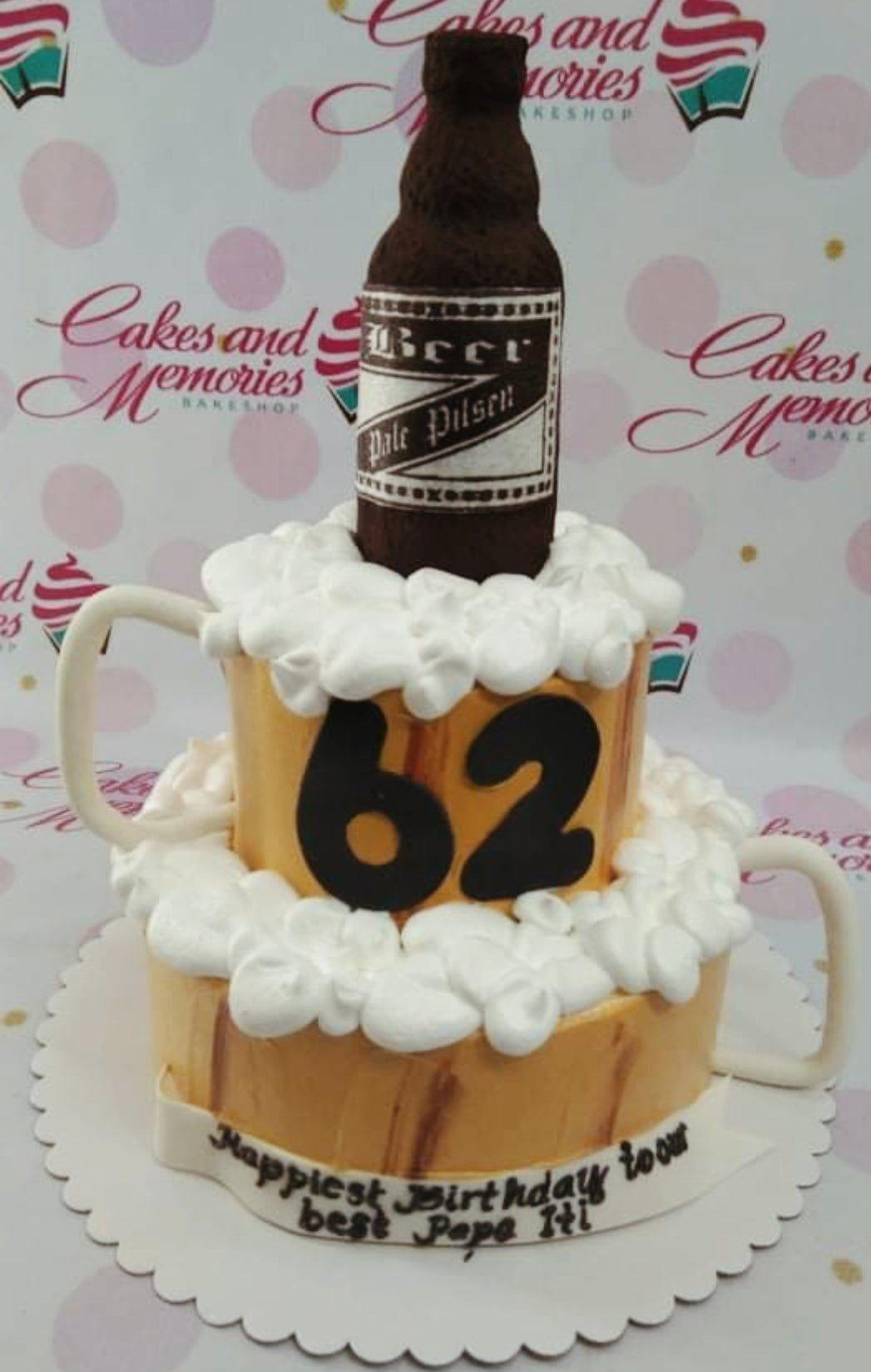 Two-tier beer mug themed birthday cake with a brown beer bottle topper and white icing foam.
