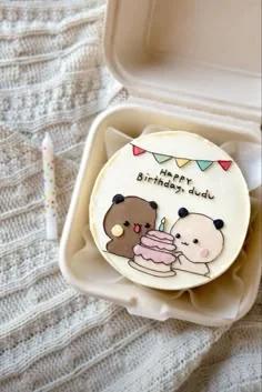 White bento cake with hand-drawn icing illustrations of a brown bear and a panda celebrating with a pink cake and colorful bunting.