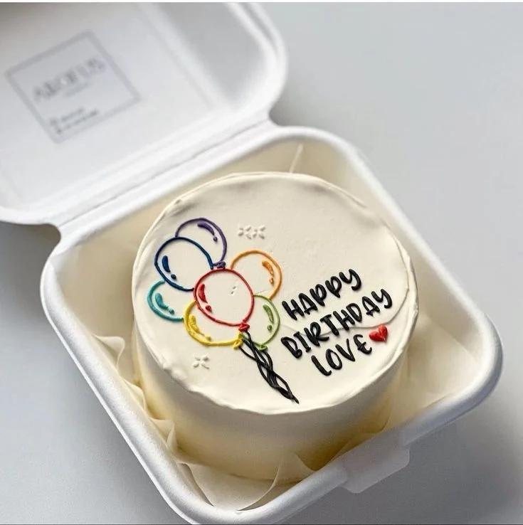 White bento cake with colorful hand-drawn icing balloons and a Happy Birthday Love message in black icing.