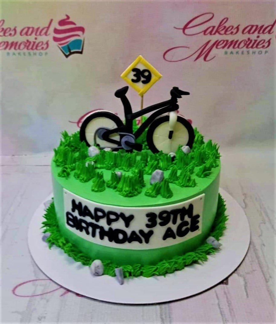 Green bicycle themed birthday cake with grass-like icing, a black bike topper, and a yellow road sign for a 39th birthday.
