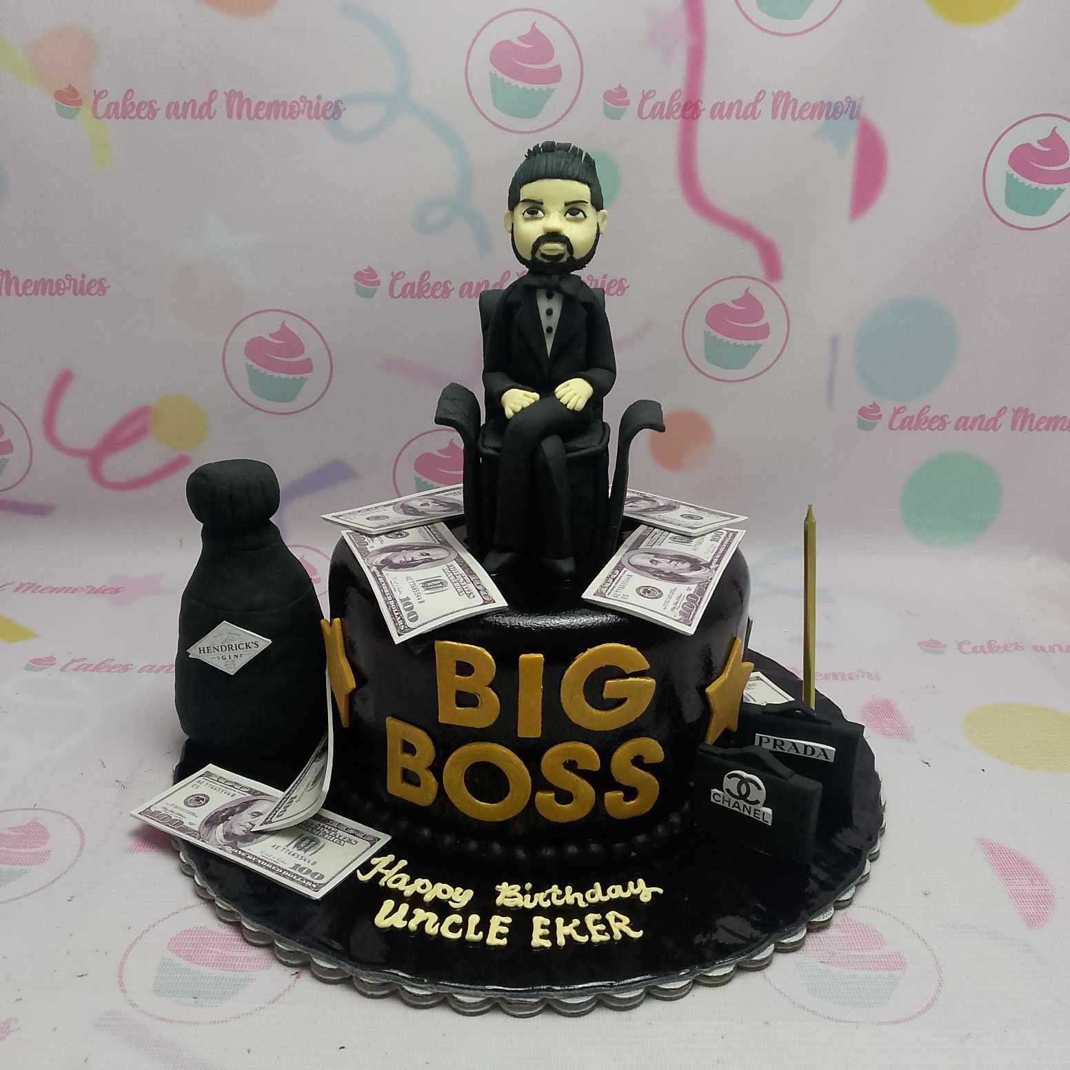 Black fondant Big Boss birthday cake with a 3D man figure sitting on a chair, edible money, and luxury shopping bag toppers.