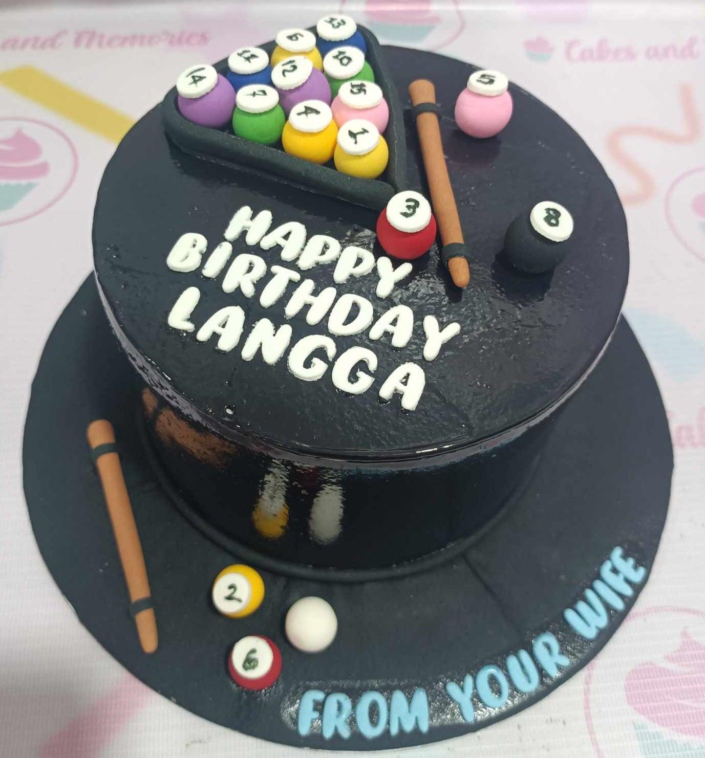 Black billiard themed birthday cake with fondant pool balls, cue sticks, and a triangle rack on a black base board.
