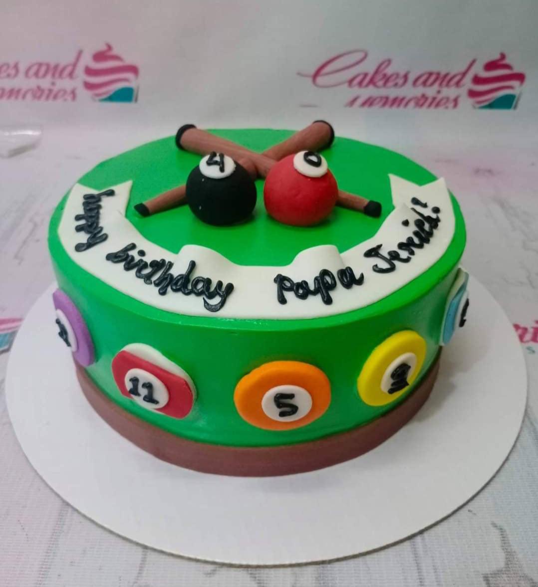 Green billiard themed birthday cake with fondant pool balls, cue sticks, and a white banner message for Papa Jerick.