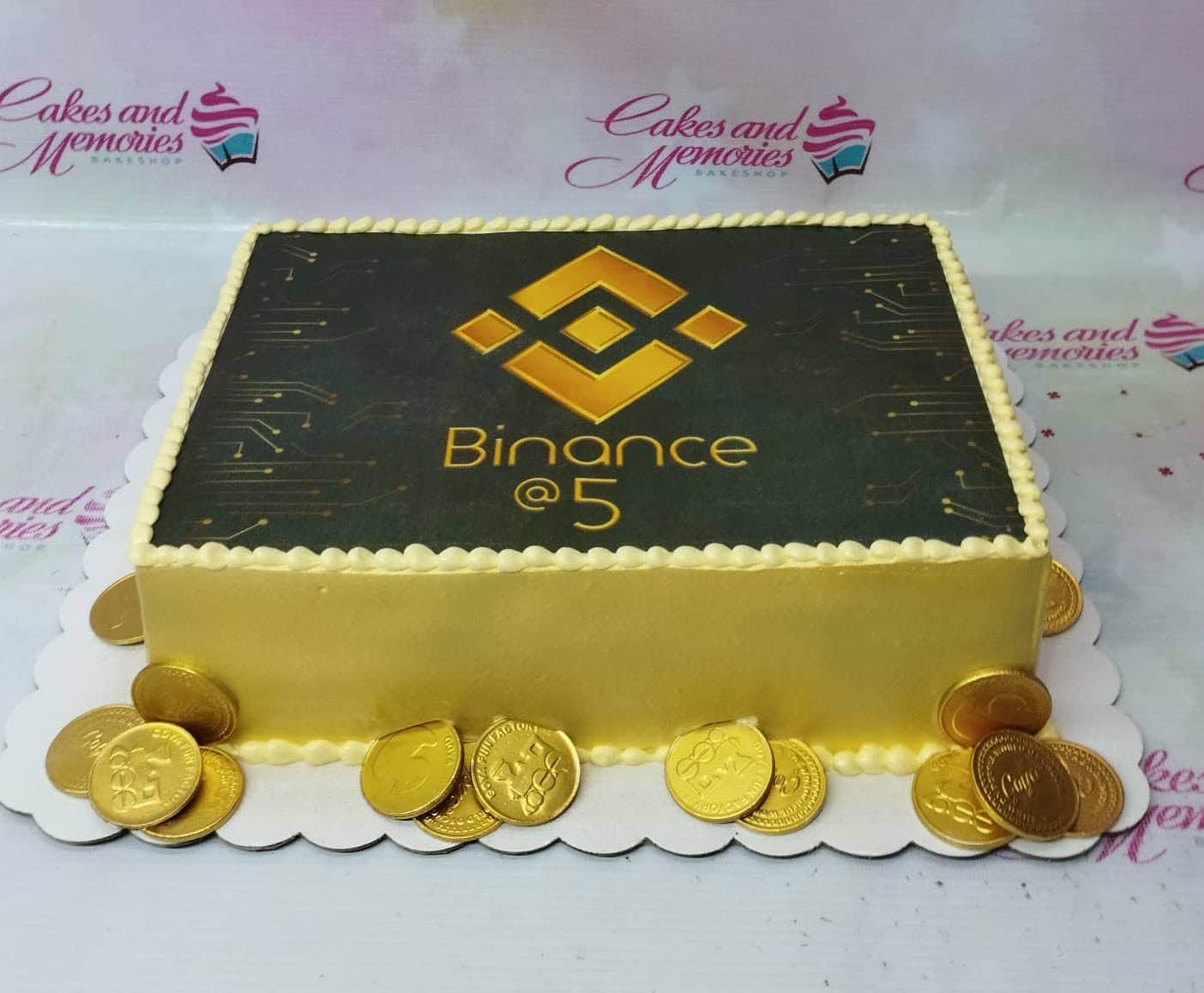 Yellow rectangle Binance 5th anniversary cake with gold chocolate coins and a printed circuit board design on top.