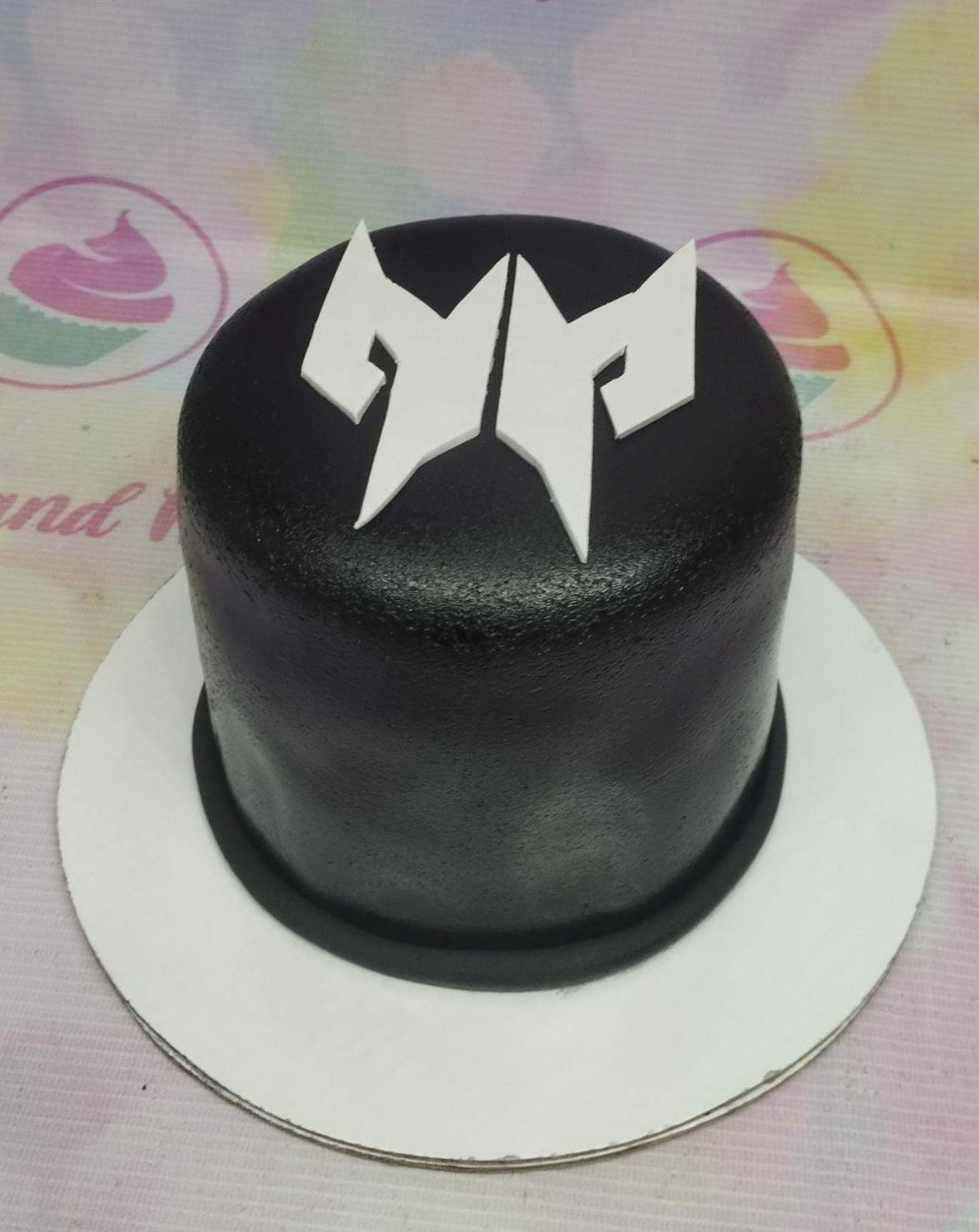 Minimalist black fondant cake with a white geometric logo topper on top.