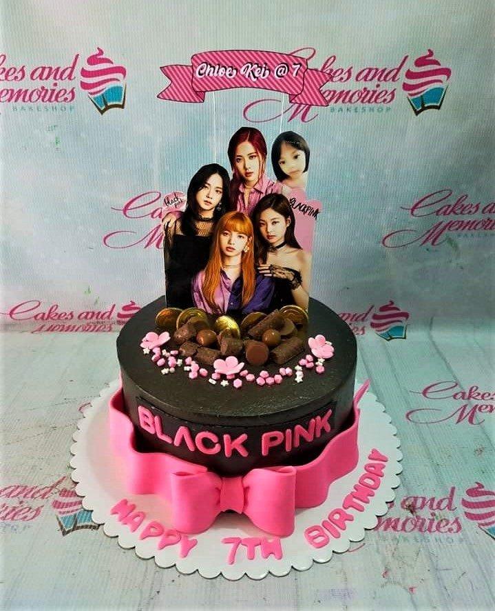 Black and pink Blackpink themed birthday cake with character printouts, chocolate decorations, and a large pink fondant bow.
