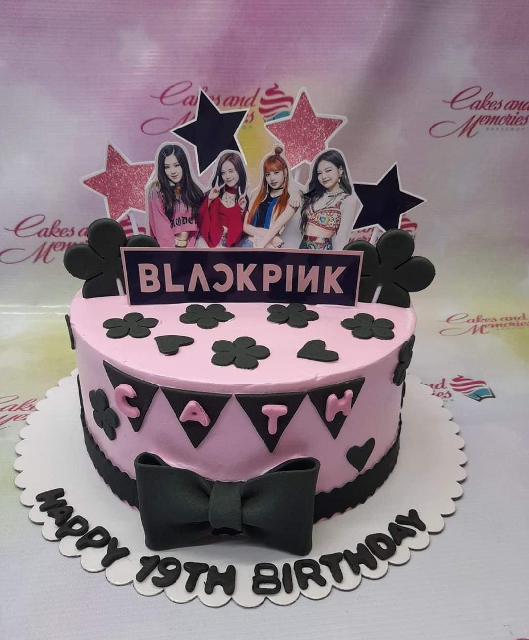 Pink Blackpink themed birthday cake with character printouts, black fondant stars, hearts, and a large black bow.