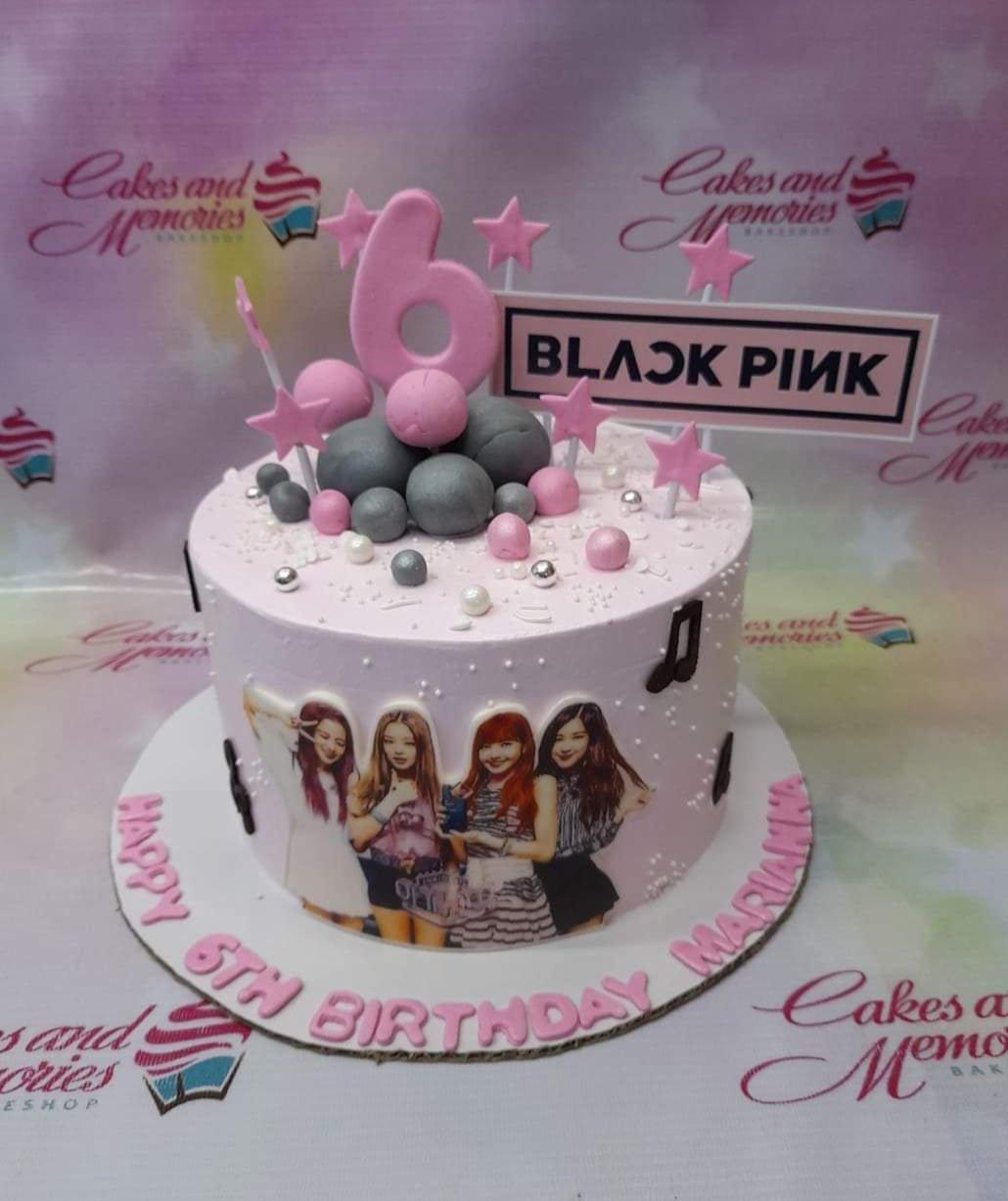 Pink Blackpink themed birthday cake with character printouts, pink stars, and grey fondant balls for a 6th birthday celebration.