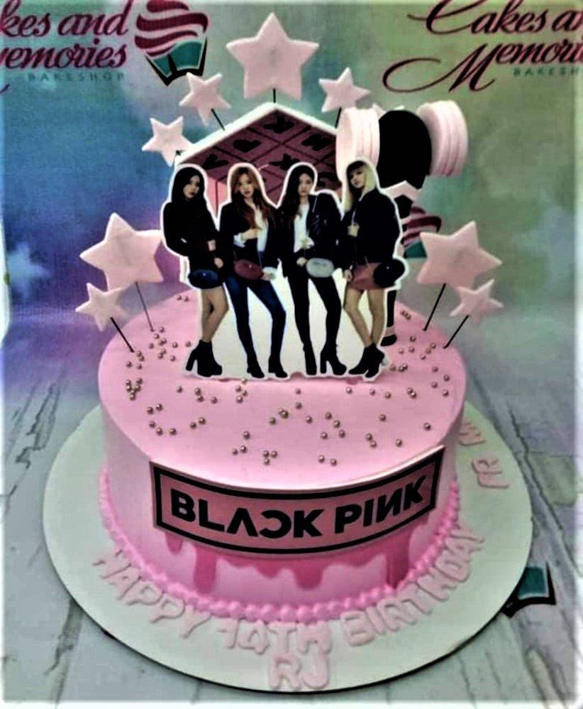 Pink Blackpink themed birthday cake with character printouts, pink stars, and silver dragees on a pink drip icing base.