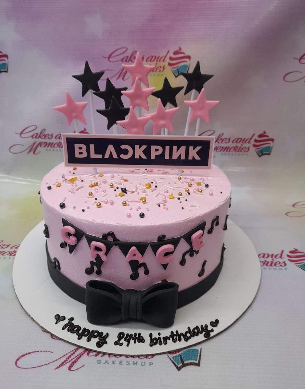 Pink Blackpink themed birthday cake with black and pink stars, music notes, and a black bow.