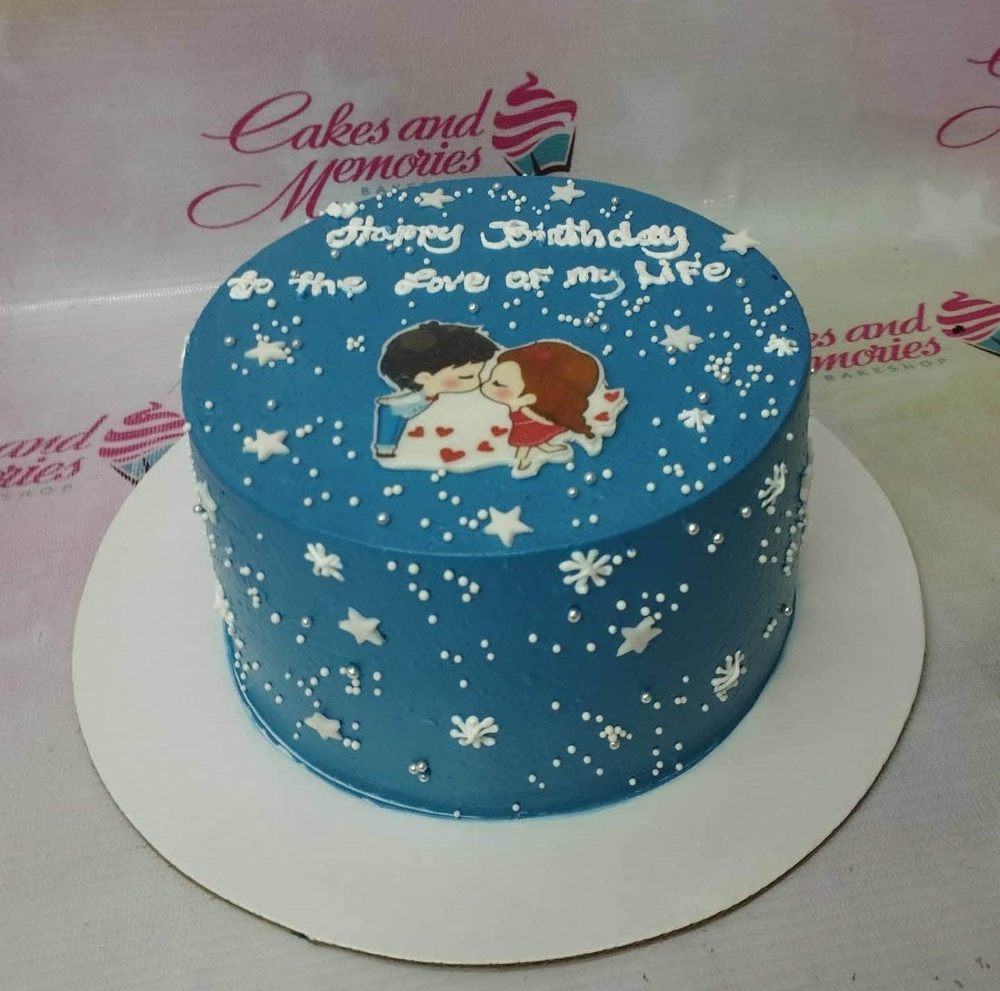 Blue minimalist birthday cake with a cute couple printout topper and white star and snowflake icing decorations.