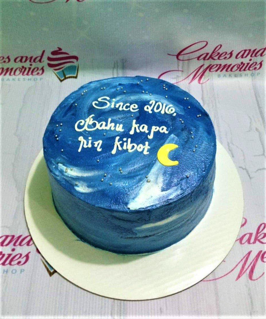 Blue galaxy bento cake with white icing text and silver dragees
