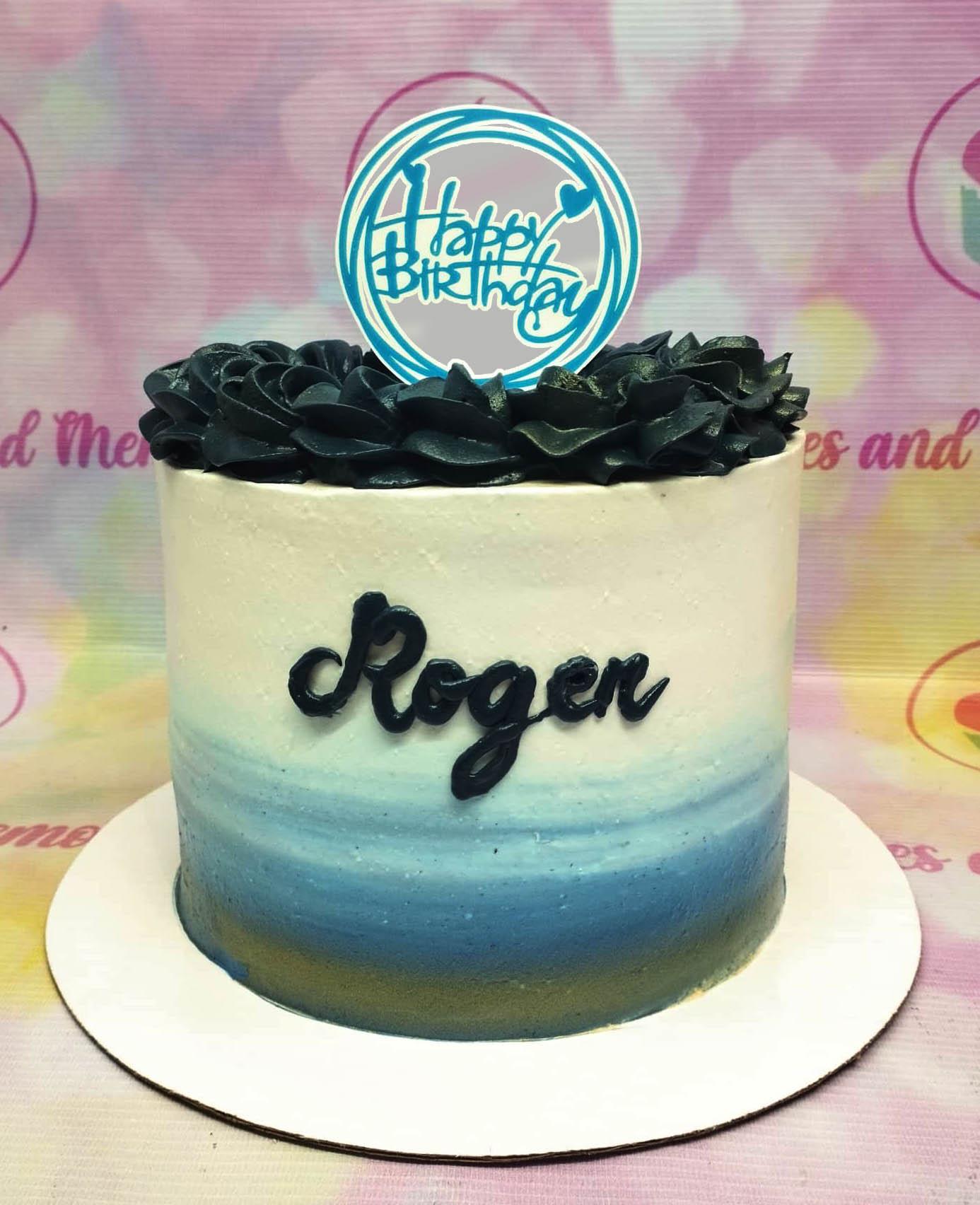A single tier birthday cake with a blue and white gradient icing, black piped rosettes on top, and a blue Happy Birthday topper.