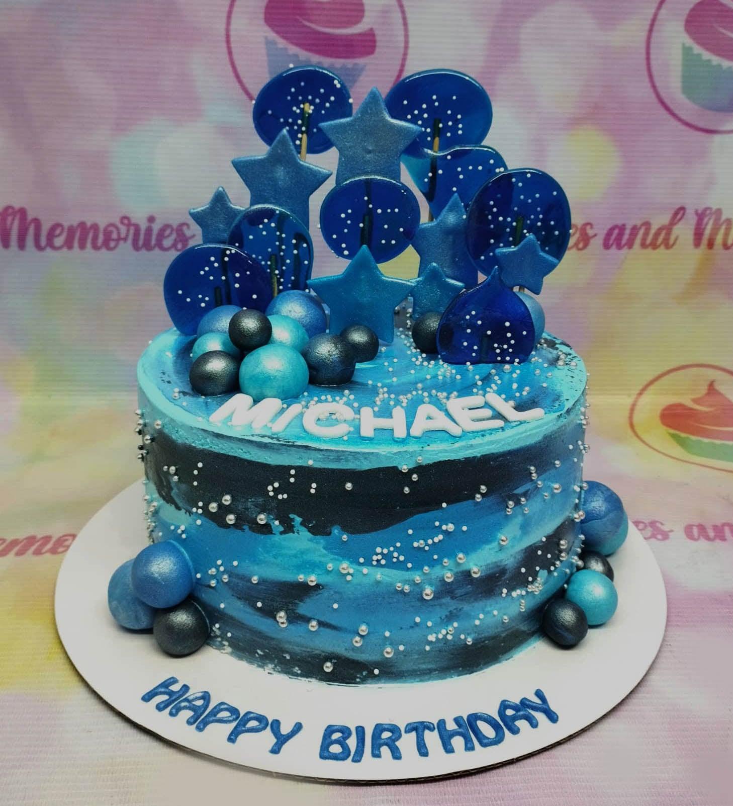 Blue and black marble effect birthday cake with blue isomalt stars and lollipops, silver dragees, and blue spheres.