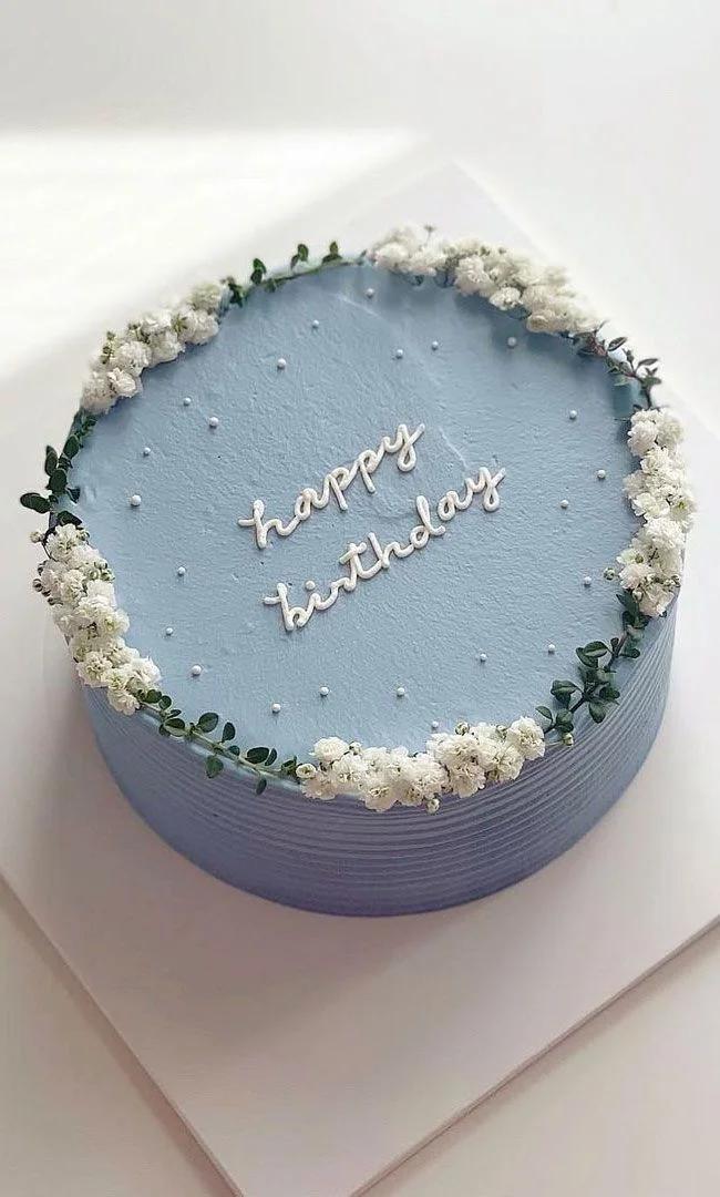 Light blue minimalist birthday cake with white baby's breath flowers and piped icing message