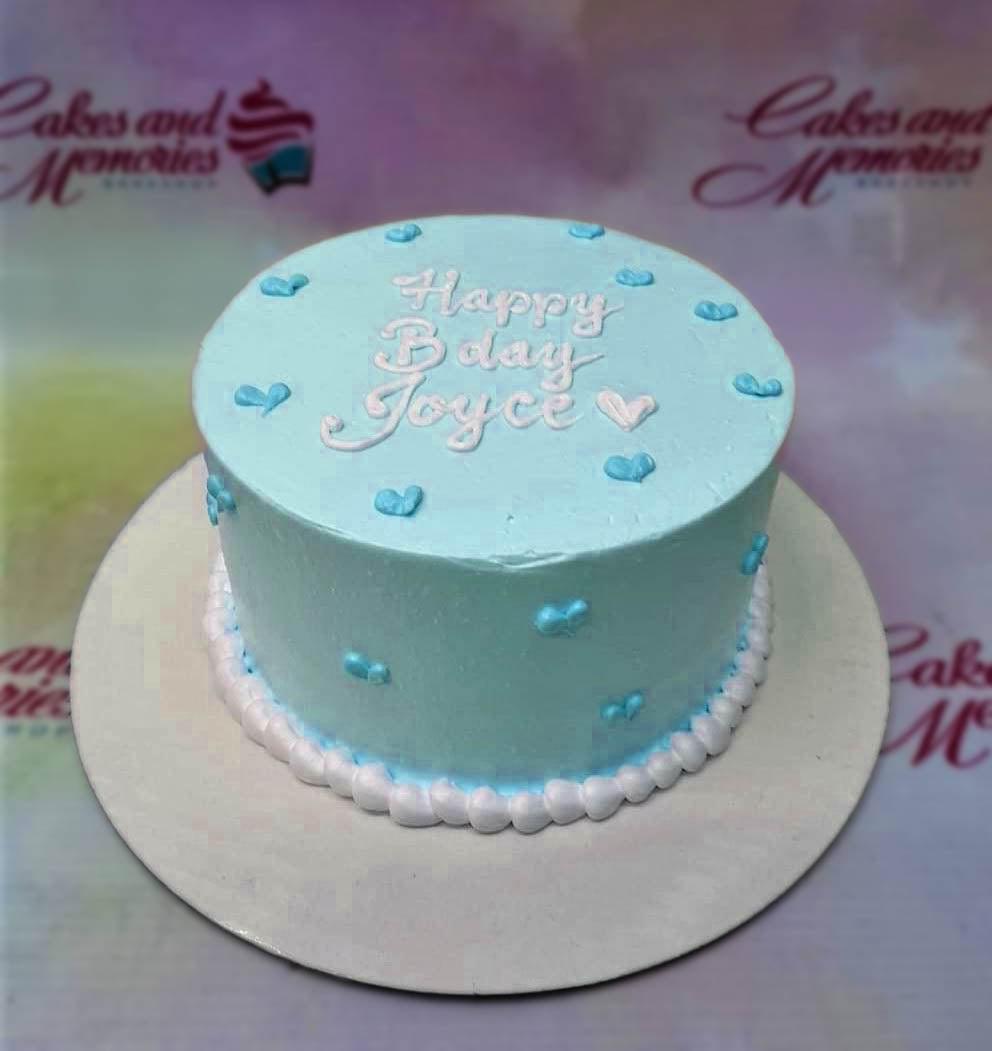 Light blue minimalist bento cake with white piped icing message and small blue heart decorations.