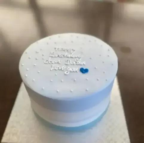 Light blue minimalist bento cake with white icing dots and a blue heart accent.