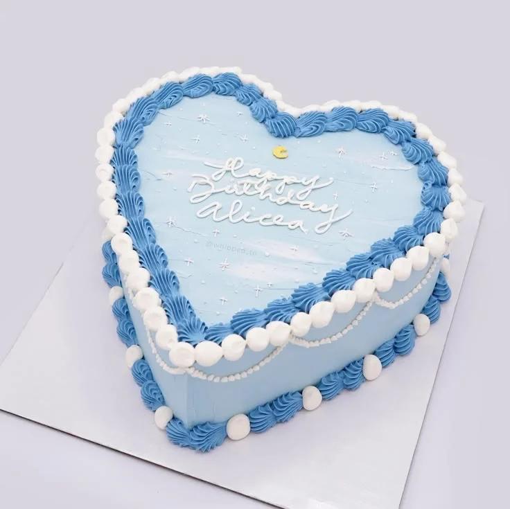 Heart-shaped light blue bento cake with white and blue piped icing borders and a crescent moon accent.