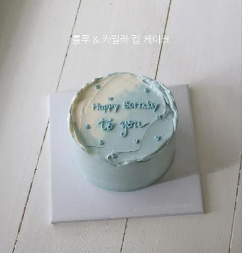 Light blue and white minimalist bento cake with textured palette knife icing and a Happy Birthday message.