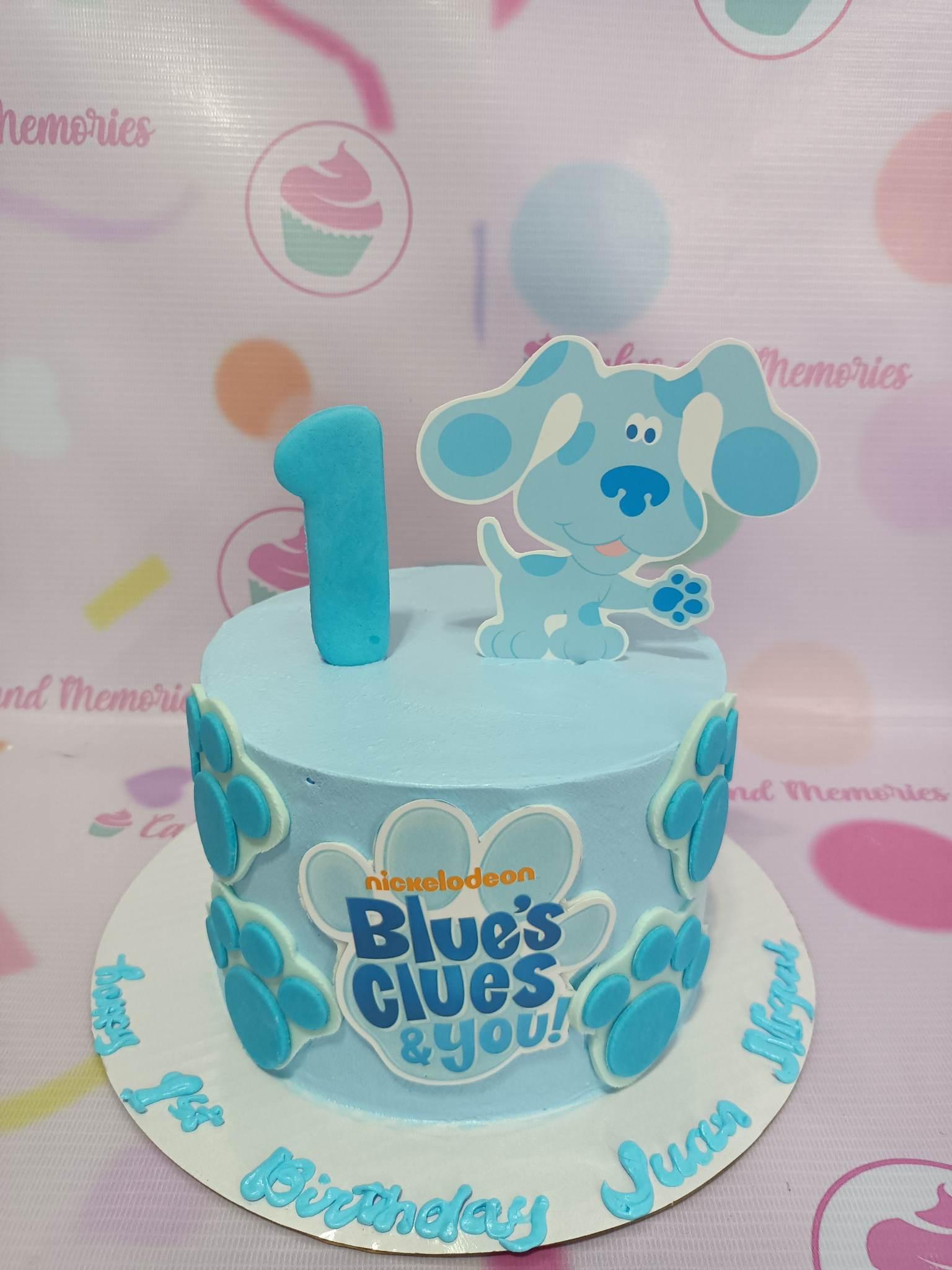 Light blue Blue's Clues themed birthday cake with a large Blue character topper, a blue number 1, and paw print decorations.