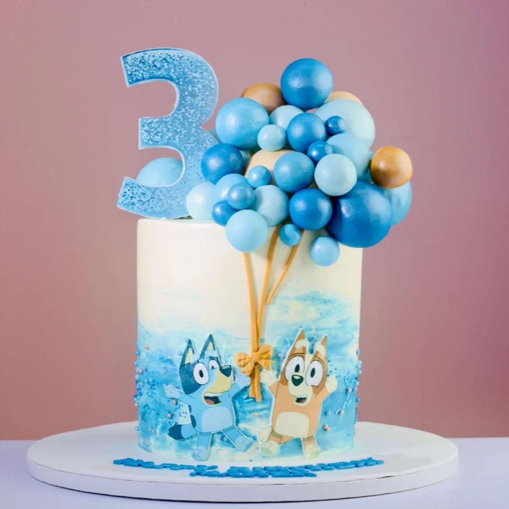 Bluey and Bingo themed birthday cake with a large blue glitter number 3 and a cluster of blue and gold balloon toppers.