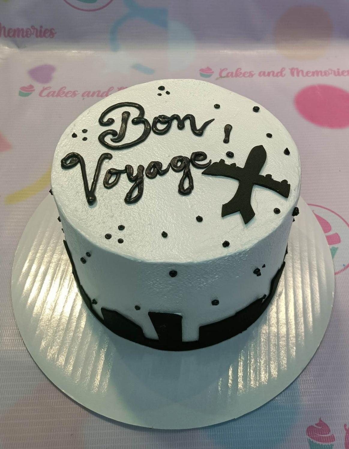 White bento cake with black piped Bon Voyage message and a black airplane silhouette decoration.