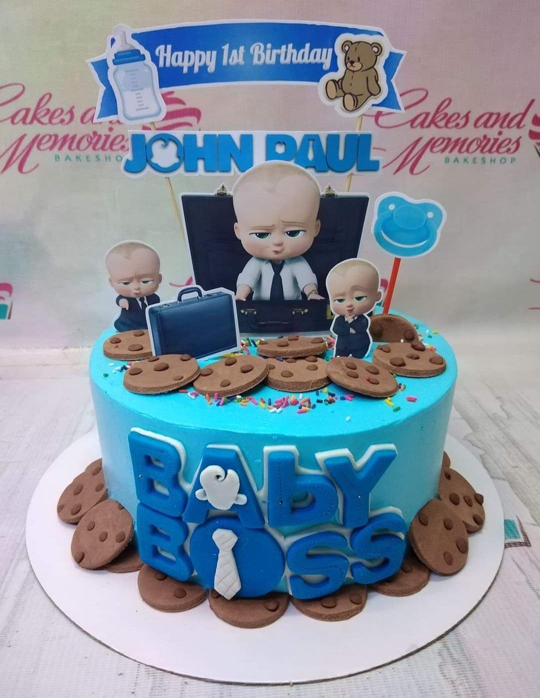 Blue Boss Baby themed birthday cake with cookie decorations and character printouts for John Paul's 1st birthday.