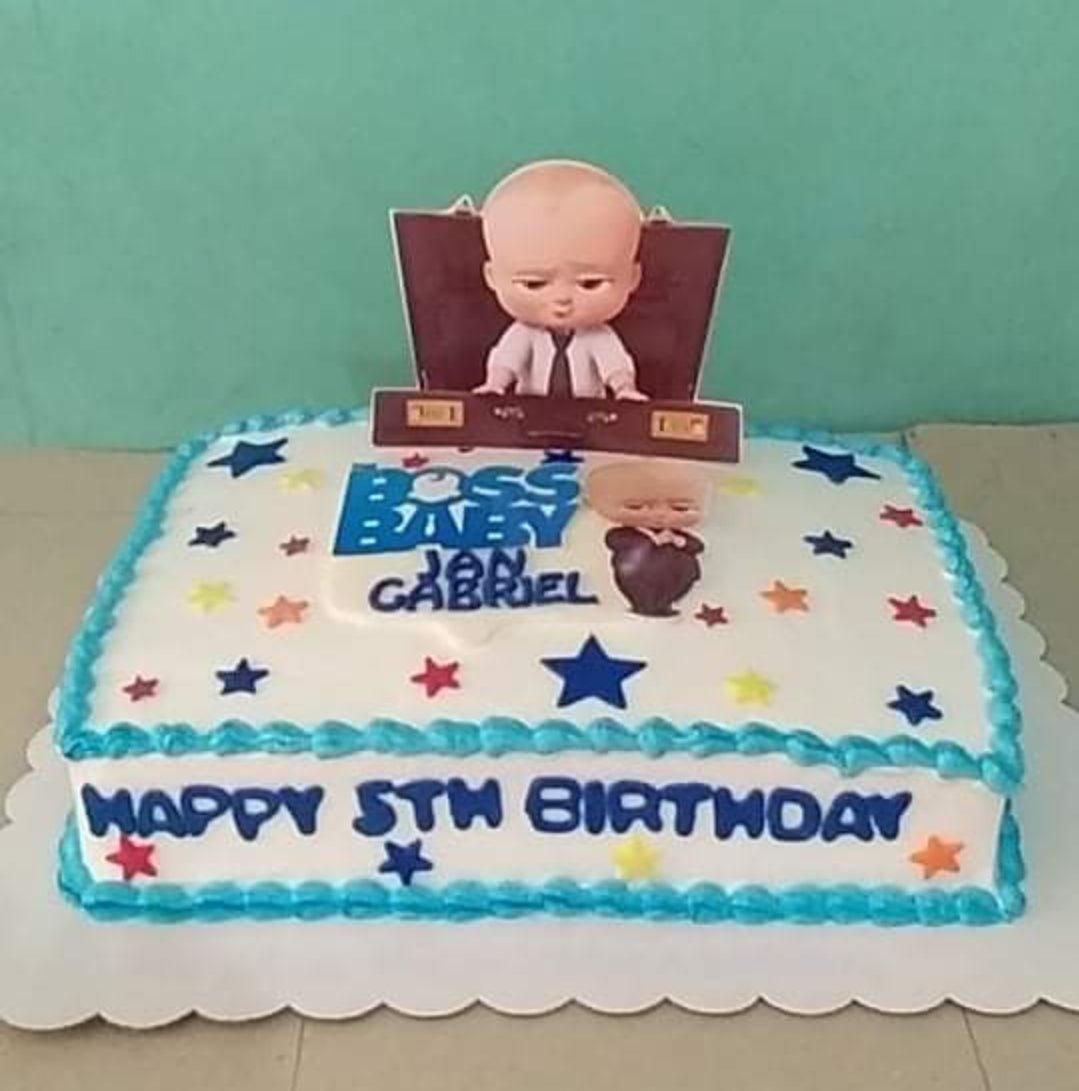 Rectangle Boss Baby birthday cake with white icing, blue borders, and colorful stars featuring a Boss Baby printout topper.