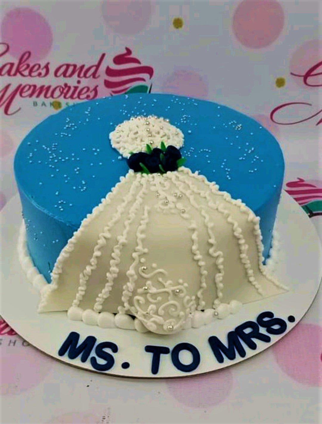 Blue single tier cake featuring a white fondant wedding dress design with navy blue roses and silver pearl sprinkles.