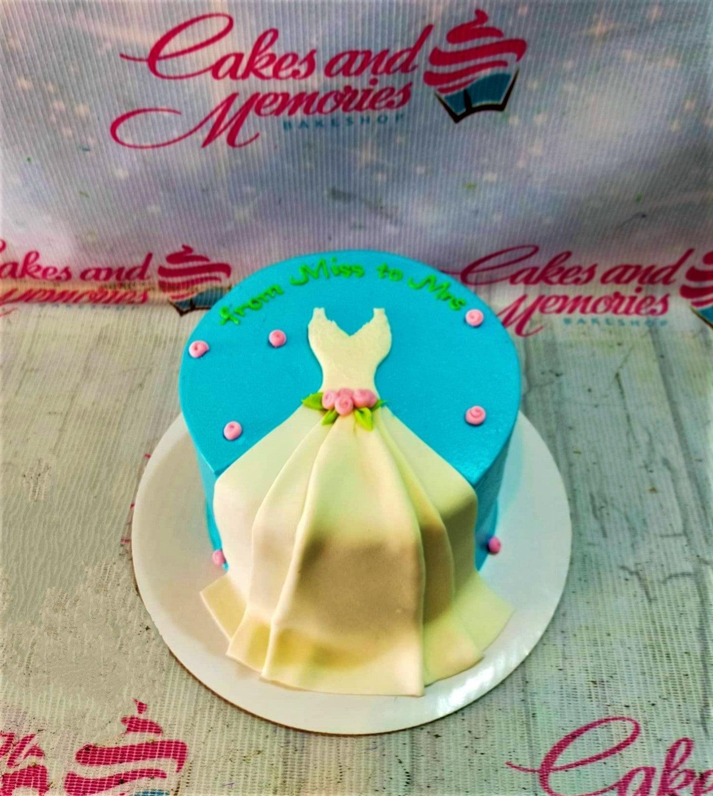 Light blue bridal shower cake featuring a white fondant wedding dress with pink roses and green leaves.