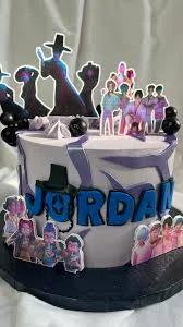 Purple and white K-pop themed birthday cake with character printouts and blue fondant name letters for Jordan.