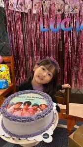 Lavender K-pop themed birthday cake with edible photo print of a boy band and purple icing ruffles.