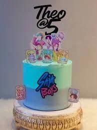 A two-tone blue and light blue cake featuring K-pop boy band printouts and a black Theo at 5 topper.