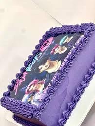 Purple rectangle cake with a K-pop group edible photo print and intricate purple icing borders.
