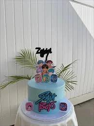 Light blue K-pop themed cake with BTS character printouts and a black name topper for Zeldiel.