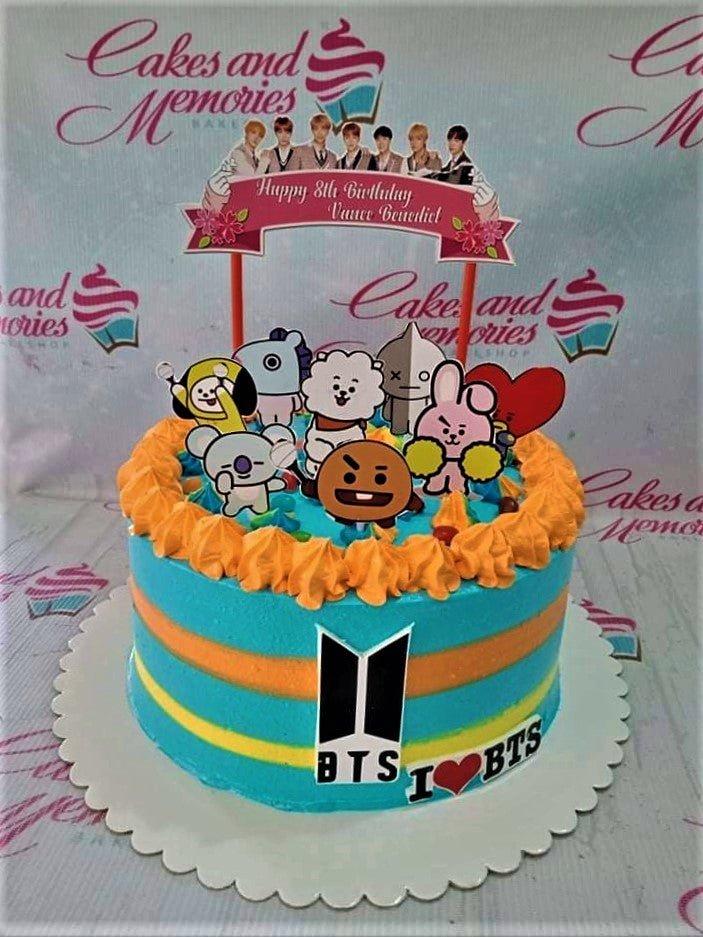 Blue and orange BTS themed birthday cake with BT21 character toppers and a BTS logo on the side.