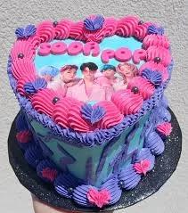 Heart-shaped light blue bento cake with pink and purple piped icing borders and a K-pop group edible photo print.