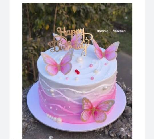 Pink and white gradient cake with gold Happy Birthday topper, pink butterflies, and white pearls.