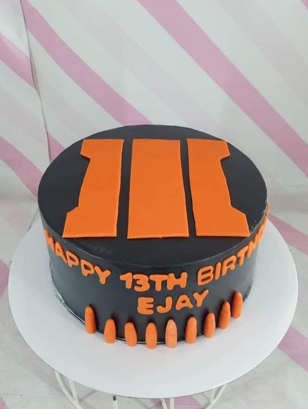 Black fondant cake with orange Call of Duty Black Ops III logo and bullet decorations for a 13th birthday.