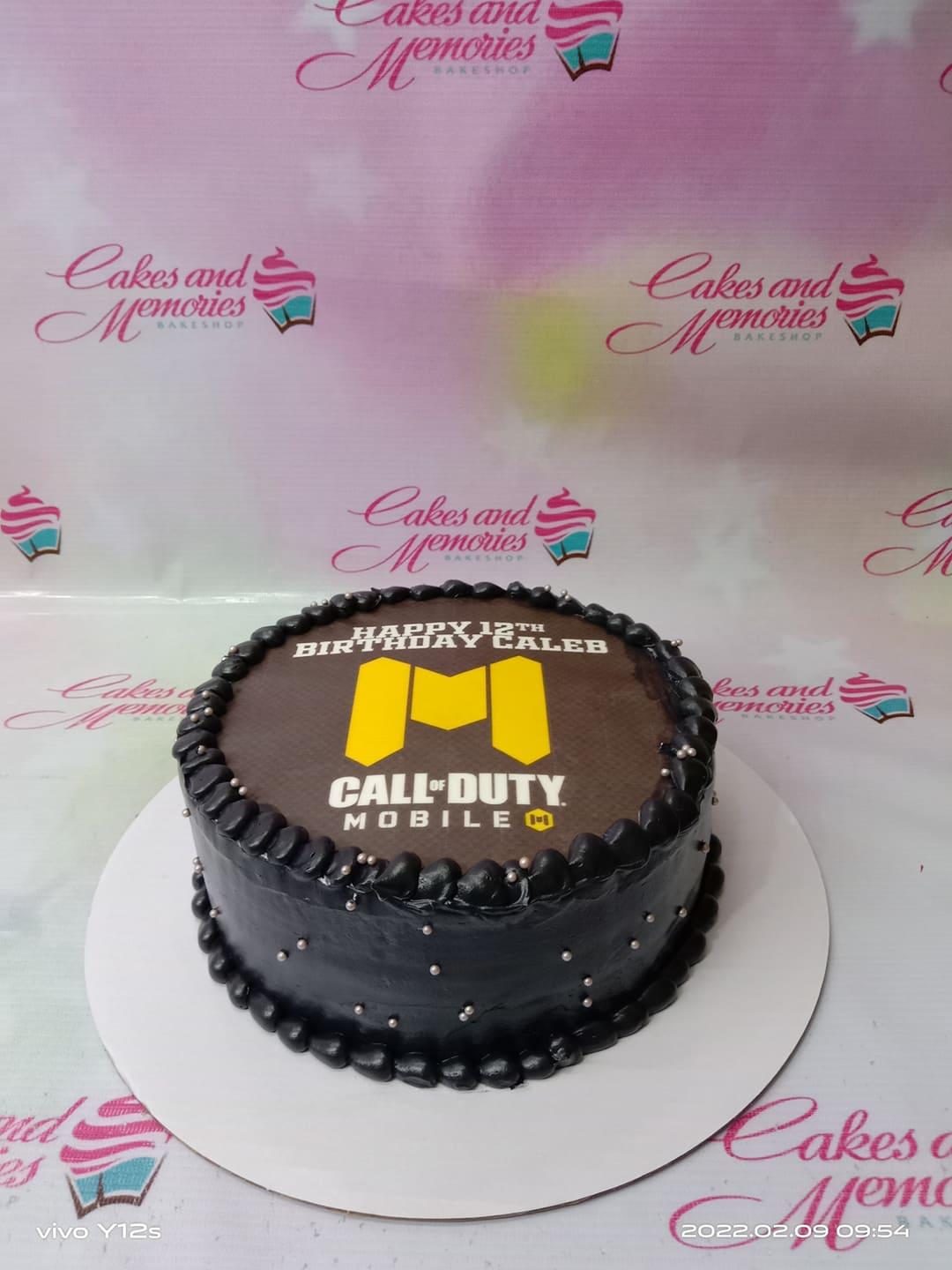 Black Call of Duty Mobile themed birthday cake with silver dragees and a large edible photo print on top.