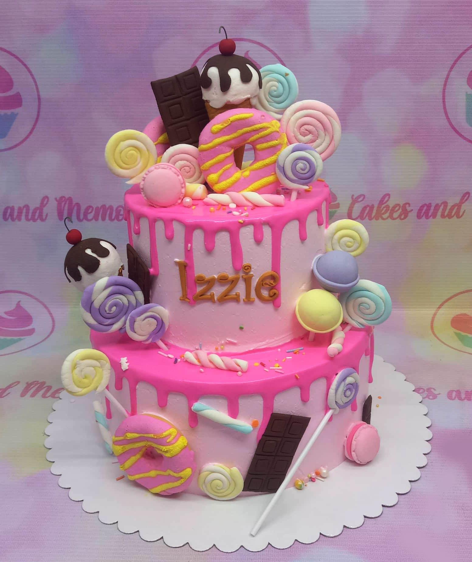 Pink 2-tier candy themed birthday cake with pink icing drips, fondant donuts, ice cream cones, lollipops, and chocolate bars.
