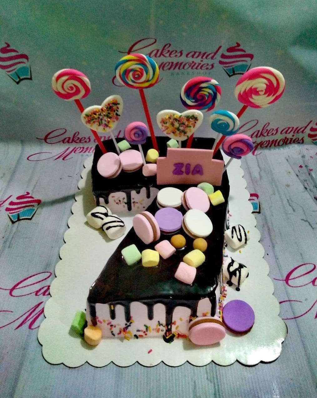 Number 7 shaped chocolate drip cake with colorful lollipops, marshmallows, and macarons for Zia's birthday.